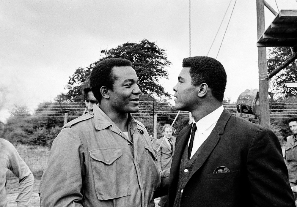 In this Aug. 5, 1966 photo, heavyweight boxer Muhammad Ali, right, visits Cleveland Browns running back and actor Jim Brown on the film set of "The Dirty Dozen" at Morkyate, Bedfordshire, England.