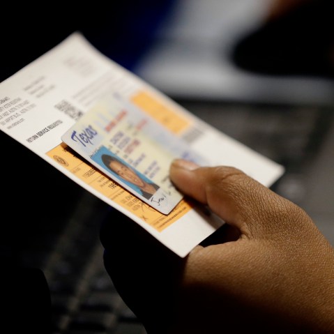 An election official checks a voter's photo identification at an early voting polling site in Austin, Texas, Feb. 26, 2014. (Photo by Eric Gay/AP)