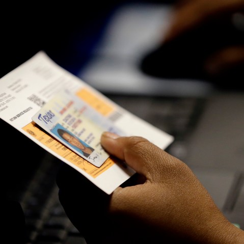An election official checks a voter's photo identification at an early voting polling site on Feb. 26, 2014 in Austin, Texas. (Photo by Eric Gay/AP)