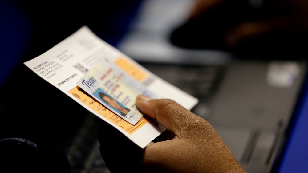 An election official checks a voter's photo identification at an early voting polling site on Feb. 26, 2014 in Austin, Texas. (Photo by Eric Gay/AP)
