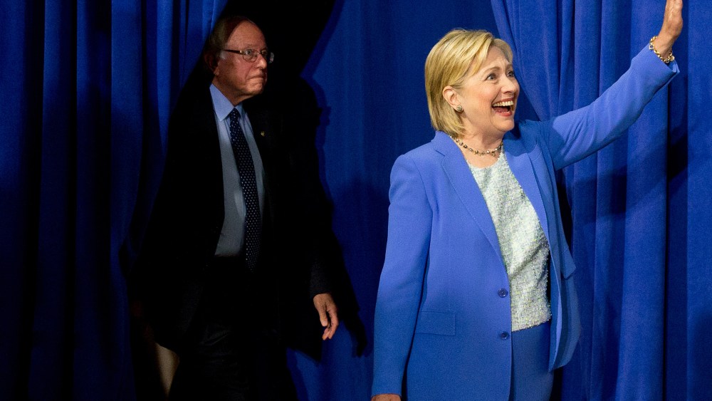 Democratic presidential candidate Hillary Clinton, followed by Sen. Bernie Sanders, I-Vt., waves as they arrive for a rally in Portsmouth, N.H., July 12, 2016, where Sanders endorsed Clinton for president. (Photo by Andrew Harnik/AP)