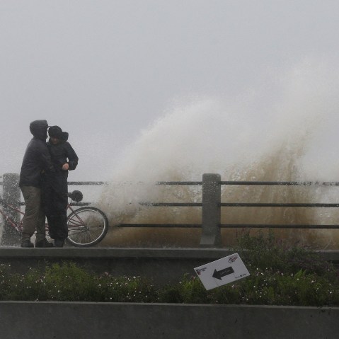 People shield themselves from a crashing wave in Charleston, S.C., Oct. 3, 2015. Rain pummeling parts of the East Coast showed little sign of slackening Saturday, with record-setting precipitation continuing through the weekend. (Photo by Chuck Burton/AP)