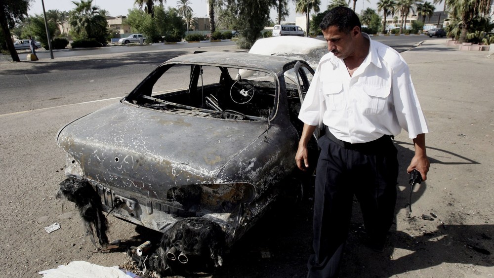 In this Sept. 25, 2007 file photo, an Iraqi traffic policeman inspects a car destroyed by a Blackwater security detail in al-Nisoor Square in Baghdad, Iraq. (Khalid Mohammed/AP)