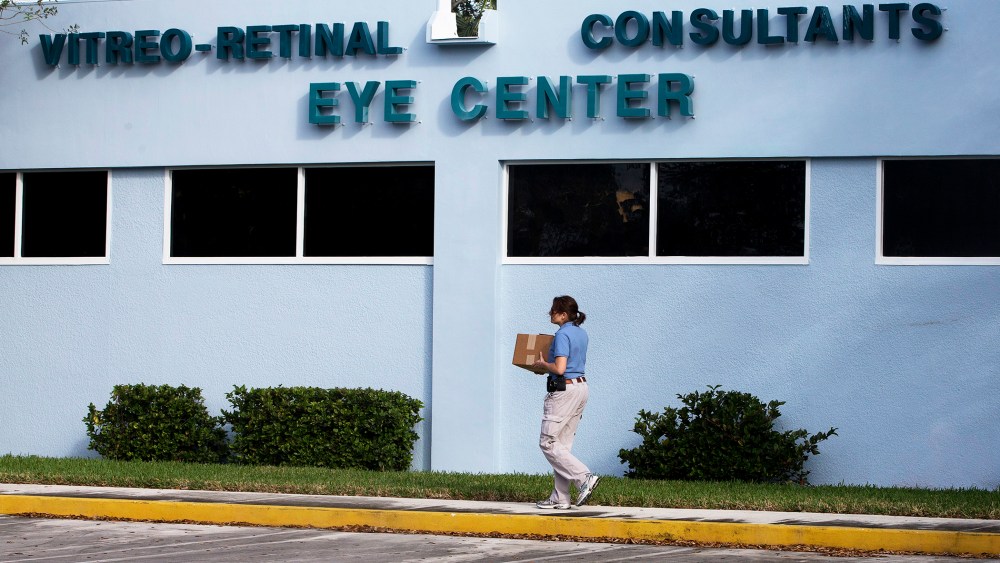 A woman carries a box of equipment into the Vitreo-Rential Consultants Eye Center in West Pam Beach, Fla., Jan. 30 2013.