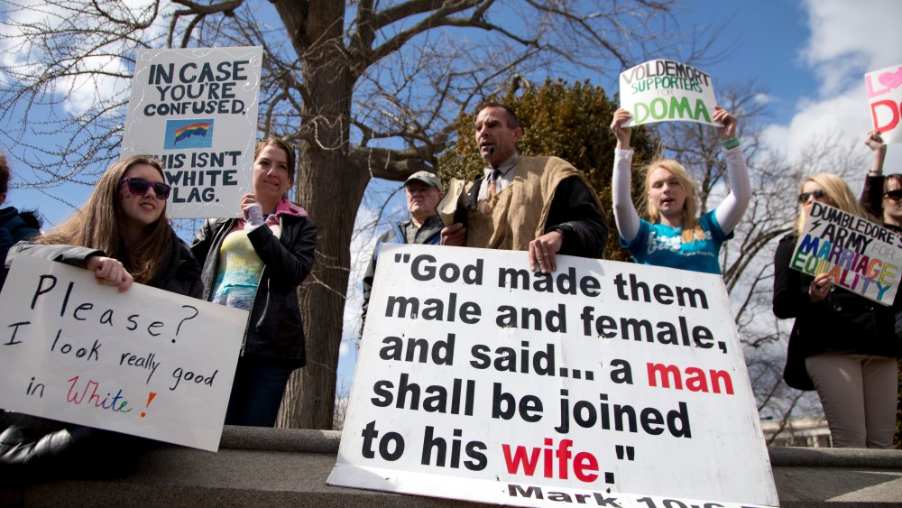 Allan Hoyle of North Carolina, with the large white sign, center, speaks out against gay marriage across from the street from the Supreme Court in Washington, Wednesday, March 27, 2013, after the court heard arguments on the Defense of Marriage Act ...