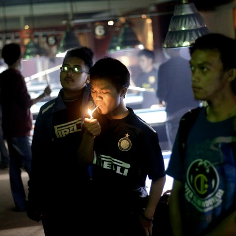 A soccer fan lights up a cigarette while watching a match at a cafe in Jakarta, Indonesia, on Oct. 27, 2013.