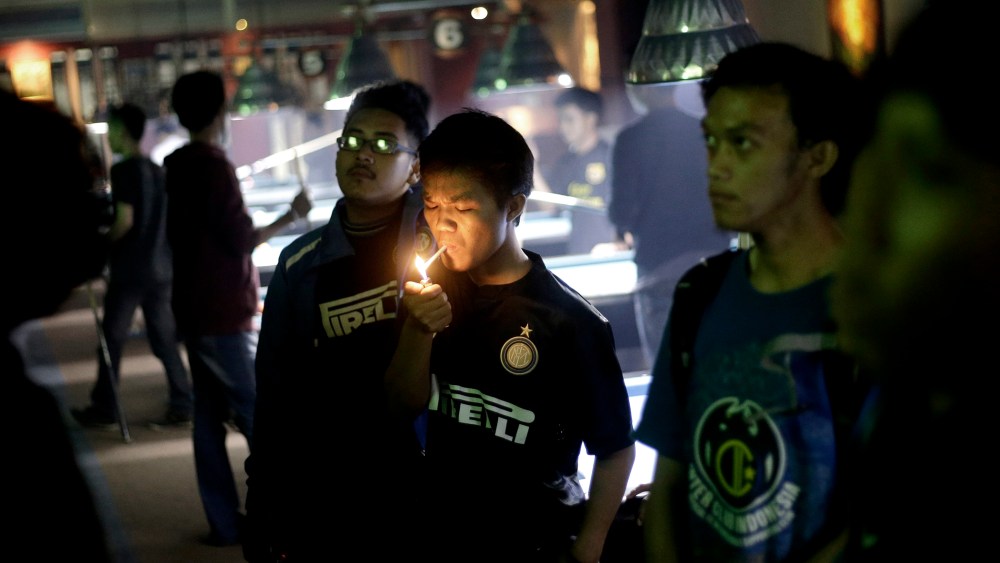 A soccer fan lights up a cigarette while watching a match at a cafe in Jakarta, Indonesia, on Oct. 27, 2013.
