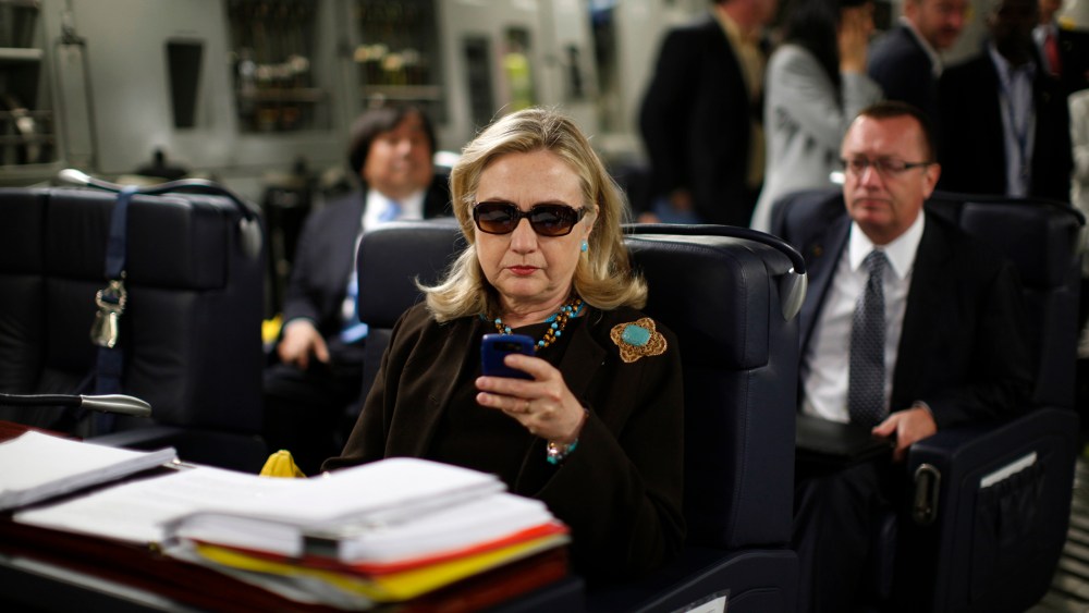 Then-Secretary of State Hillary Rodham Clinton checks her Blackberry from a desk inside a C-17 military plane upon her departure from Malta, in the Mediterranean Sea, bound for Tripoli, Libya on Oct. 18, 2011. (Photo by Kevin Lamarque/Pool/AP)