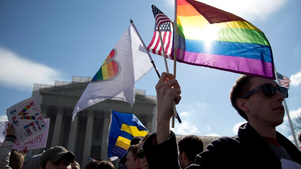 Kevin Coyne of Washington holds flags in front of the Supreme Court in Washington. (Photo by Carolyn Kaster/AP)