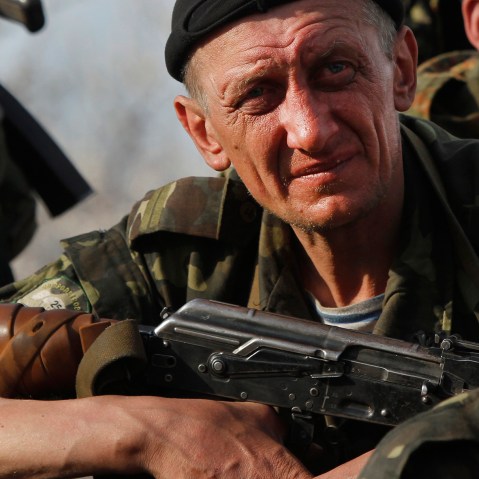 Soldiers from the Ukrainian Army sit atop combat vehicles as they are blocked by people on their way to the town of Kramatorsk, Wednesday, April 16, 2014.