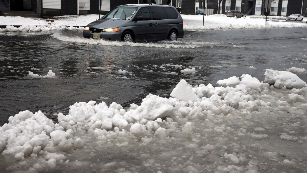 A van drives through a flooded street as ice and snow prevent drainage, Jan. 23, 2016, in Atlantic City, N.J. (Photo by Mel Evans/AP)
