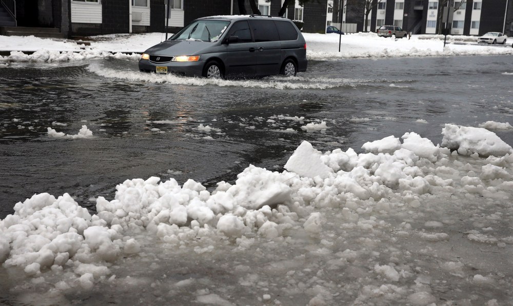 A van drives through a flooded street as ice and snow prevent drainage, Jan. 23, 2016, in Atlantic City, N.J. (Photo by Mel Evans/AP)