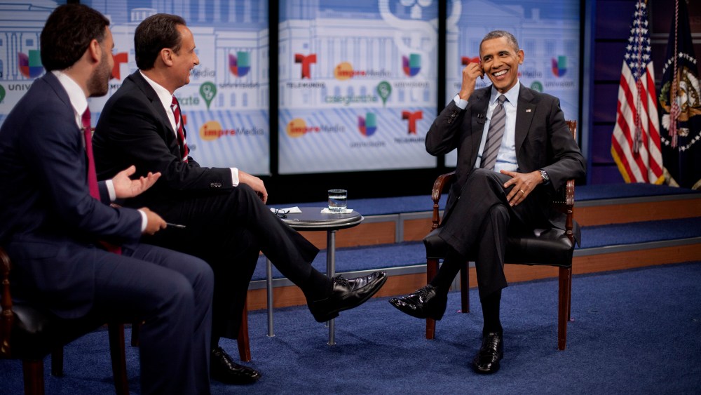 President Barack Obama adjusts his earpiece during a town hall event with television hosts Jose Diaz Balart and Enrique Acevedo, far left, at the Newseum in Washington, on March 6, 2014.