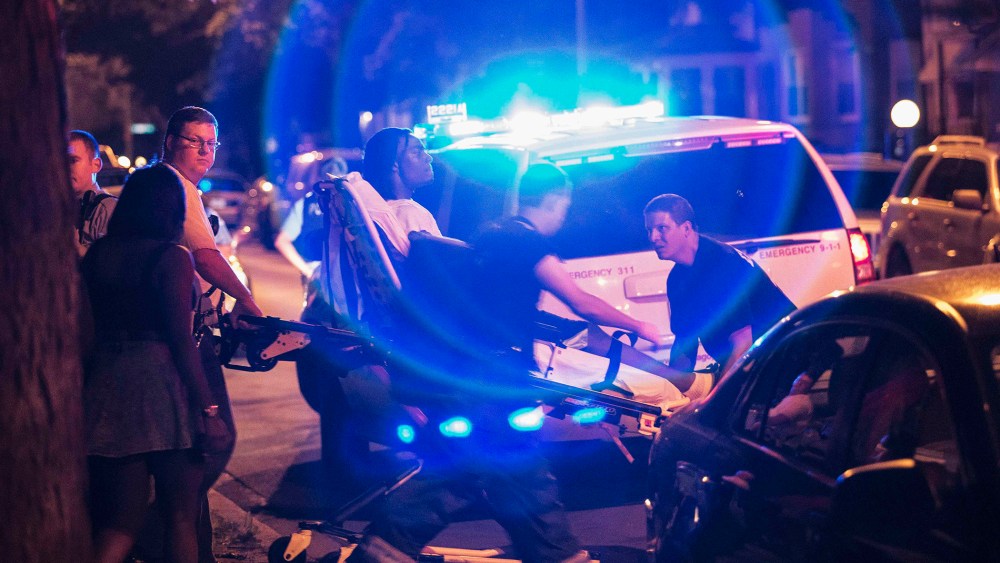 In this Sunday, July 6, 2014 photo, a man is wheeled on a stretcher after being shot in the leg on Chicago's South Side.