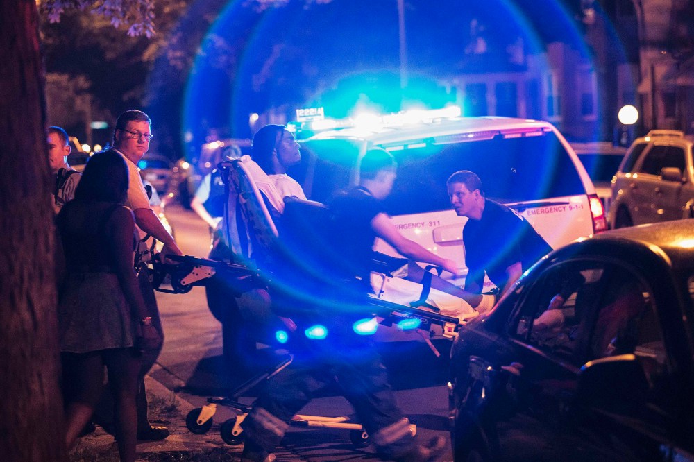 In this Sunday, July 6, 2014 photo, a man is wheeled on a stretcher after being shot in the leg on Chicago's South Side.