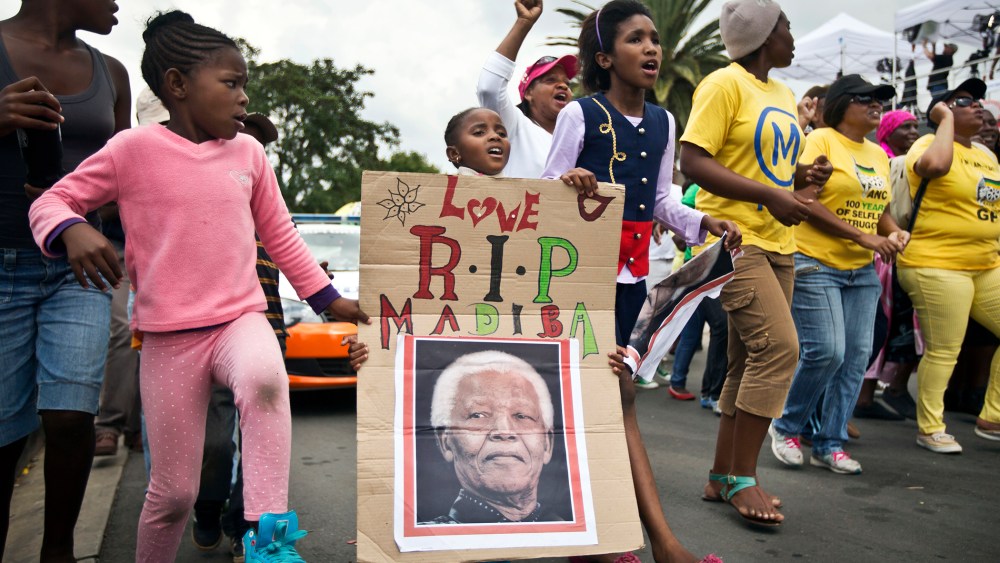 A young girl marches with others to celebrate Nelson Mandela's life, in the street outside his old house in Soweto, Johannesburg, South Africa, Dec. 6, 2013.
