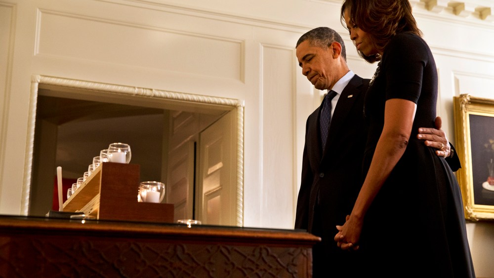 President Barack Obama and first lady Michelle Obama take a moment of silence in honor of the Newtown shooting victims on the one year anniversary of the tragedy, at the White House in Washington, Dec. 14, 2013.