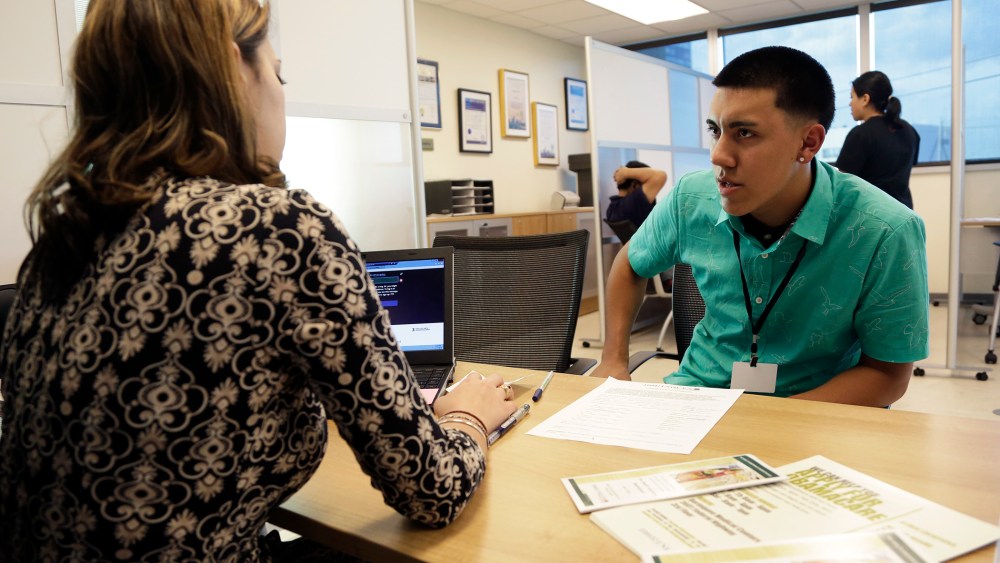 Navigator Dianelys Dominguez, left, assists Giovanny Vega, 18, of Miami, right, sign up for health insurance under the Affordable Care Act, Nov. 17, 2014, in Miami, Fla. (Photo by Lynne Sladky/AP)