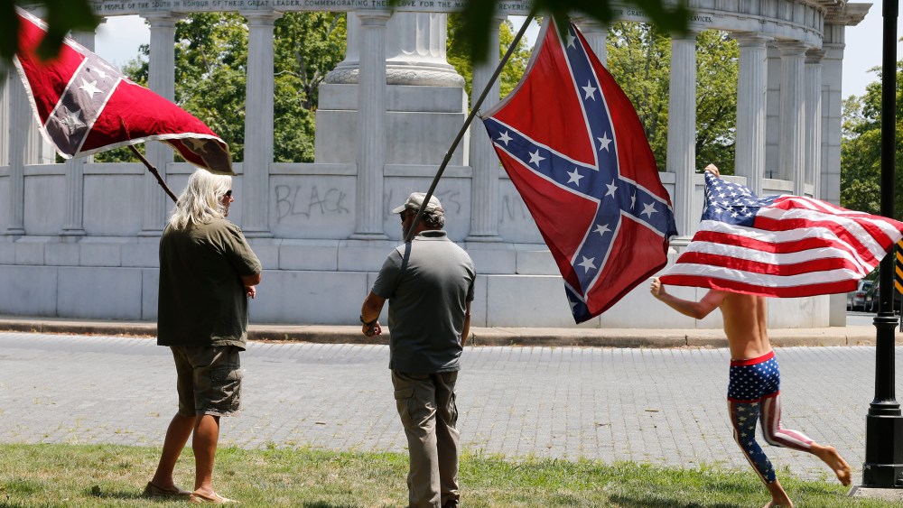 Members of the Virginia Flaggers demonstrate near the monument for Confederacy President Jefferson Davis as a runner carries an American flag, June 25, 2015, on Monument Avenue in Richmond, Va. (Photo by Steve Helber/AP)