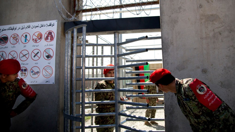 Afghan National Army soldiers peek through the gate of the Parwan Detention Facility in Bagram, Afghanistan, on March 25, 2013.