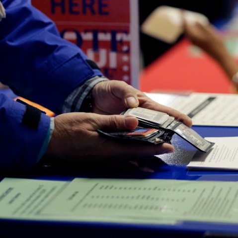 A voter shows his photo identification to an election official at an early voting polling site, in Austin, Texas on Feb. 26, 2014. (Eric Gay/AP)