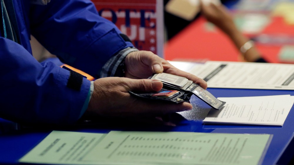 A voter shows his photo identification to an election official at an early voting polling site, in Austin, Texas on Feb. 26, 2014. (Eric Gay/AP)