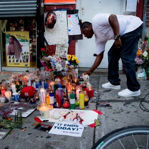 A mourner places a candle at a memorial for Eric Garner, a Staten Island man who died while being arrested by New York City police, on July 22, 2014, in New York. (Photo by John Minchillo/AP)