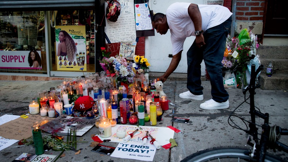 A mourner places a candle at a memorial for Eric Garner, a Staten Island man who died while being arrested by New York City police, on July 22, 2014, in New York. (Photo by John Minchillo/AP)