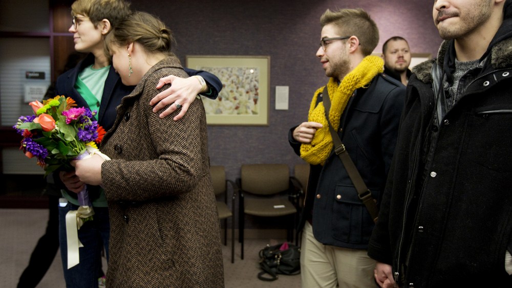 Same-sex couples Natalie Dicou, left, and Nichole Christensen, middle left, and James Goodman, middle right, and Jeffrey Gomez, right, wait in line to get a marriage license at the Salt Lake County Clerk's Office in Salt Lake City, Dec. 20, 2013.