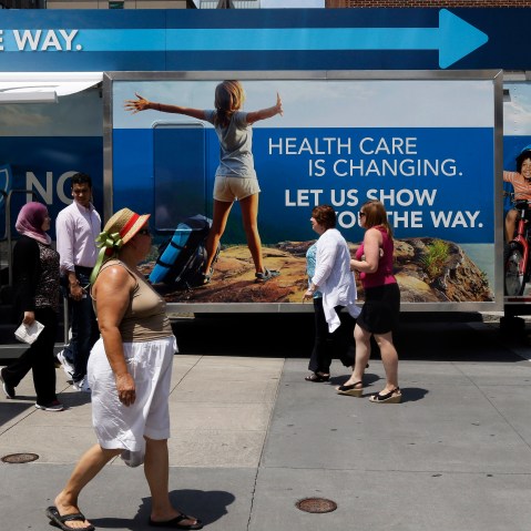 Pedestrians pass by a Blue Cross Blue Shield of North Carolina trailer at the downtown farmer's market in Raleigh, N.C., July 17, 2013.