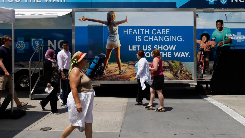 Pedestrians pass by a Blue Cross Blue Shield of North Carolina trailer at the downtown farmer's market in Raleigh, N.C., July 17, 2013.
