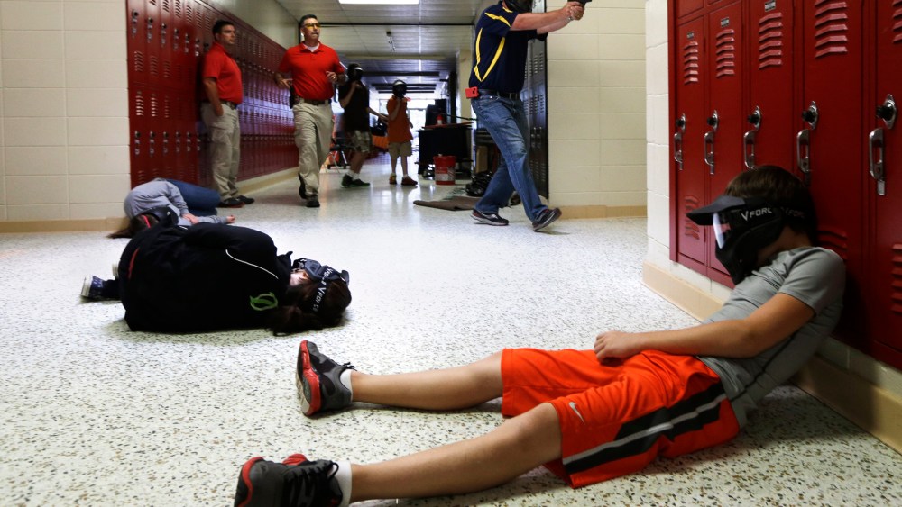 A Clarksville Schools faculty member carries an air-powered practice handgun during a training exercise in Clarksville, Ark., July 11, 2013.