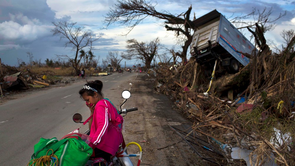 A woman rests on a roadside with her family's belongings near the Typhoon Haiyan ravaged town of Tacloban