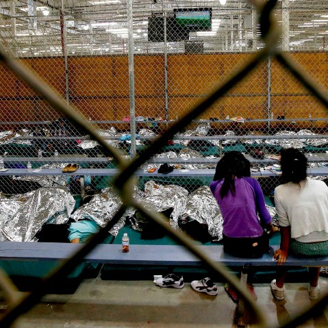 Two young girls watch a World Cup soccer match on a television from their holding area at the U.S. Customs and Border Protection Nogales Placement Center on June 18, 2014, in Nogales, Ariz. (Photo by Ross D. Franklin/AP)