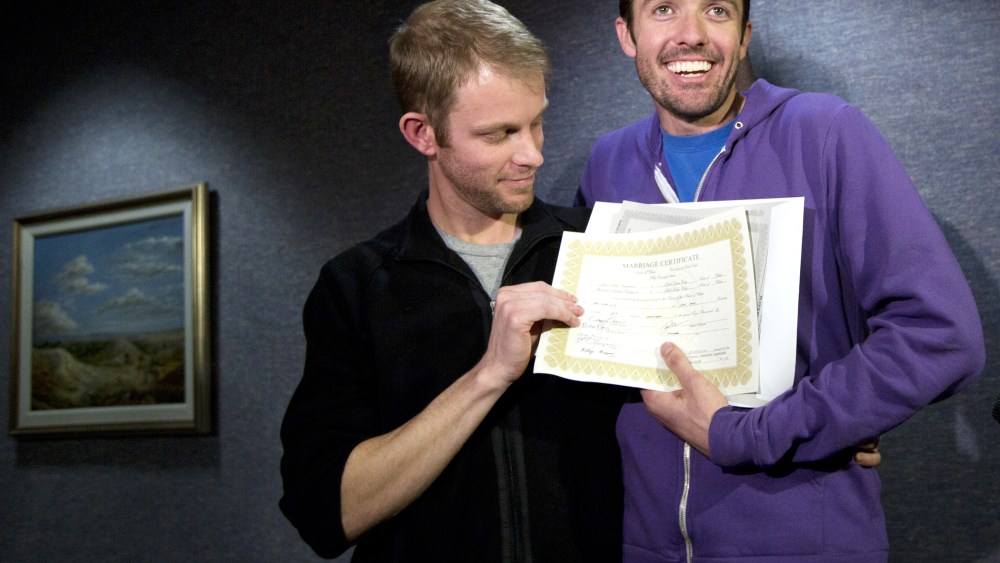 Seth Anderson, left, and Michael Ferguson, right, hold up their marriage certificate and license outside of the Salt Lake County Clerk's Office in Salt Lake City, Dec. 20, 2013.