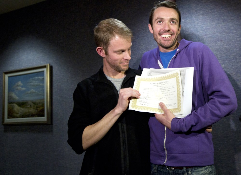 Seth Anderson, left, and Michael Ferguson, right, hold up their marriage certificate and license outside of the Salt Lake County Clerk's Office in Salt Lake City, Dec. 20, 2013.