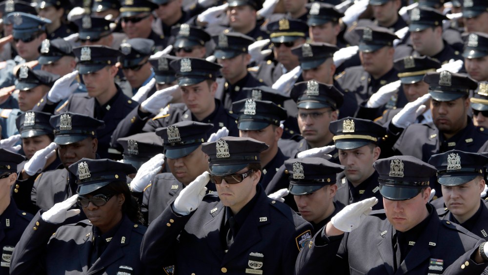Police officers salute as the procession for New York City Police officer Brian Moore passes after his funeral mass, May 8, 2015, at the St. James Roman Catholic church in Seaford, N.Y. (Photo by Mary Altaffer/AP)