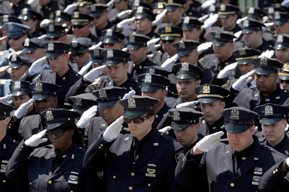 Police officers salute as the procession for New York City Police officer Brian Moore passes after his funeral mass, May 8, 2015, at the St. James Roman Catholic church in Seaford, N.Y. (Photo by Mary Altaffer/AP)