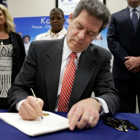 Gov. Sam Brownback signs a welfare reform bill into law in Topeka, Kan., April 16, 2015. (Photo by Orlin Wagner/AP)