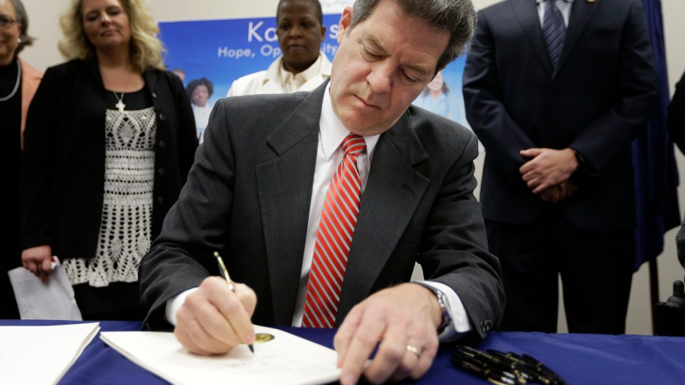 Gov. Sam Brownback signs a welfare reform bill into law in Topeka, Kan., April 16, 2015. (Photo by Orlin Wagner/AP)