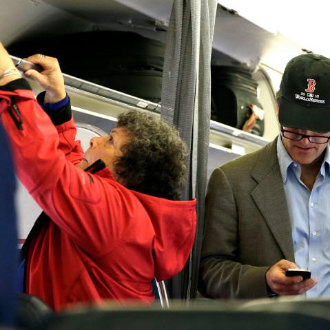 In this  Oct. 31, 2013 file photo, a passenger checks his cell phone while boarding a flight, in Boston.