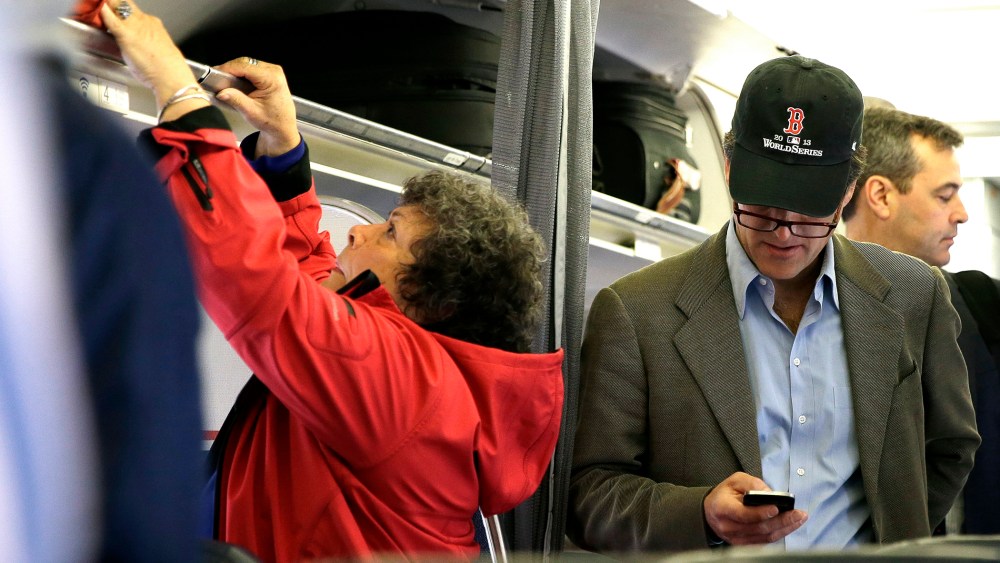 In this  Oct. 31, 2013 file photo, a passenger checks his cell phone while boarding a flight, in Boston.