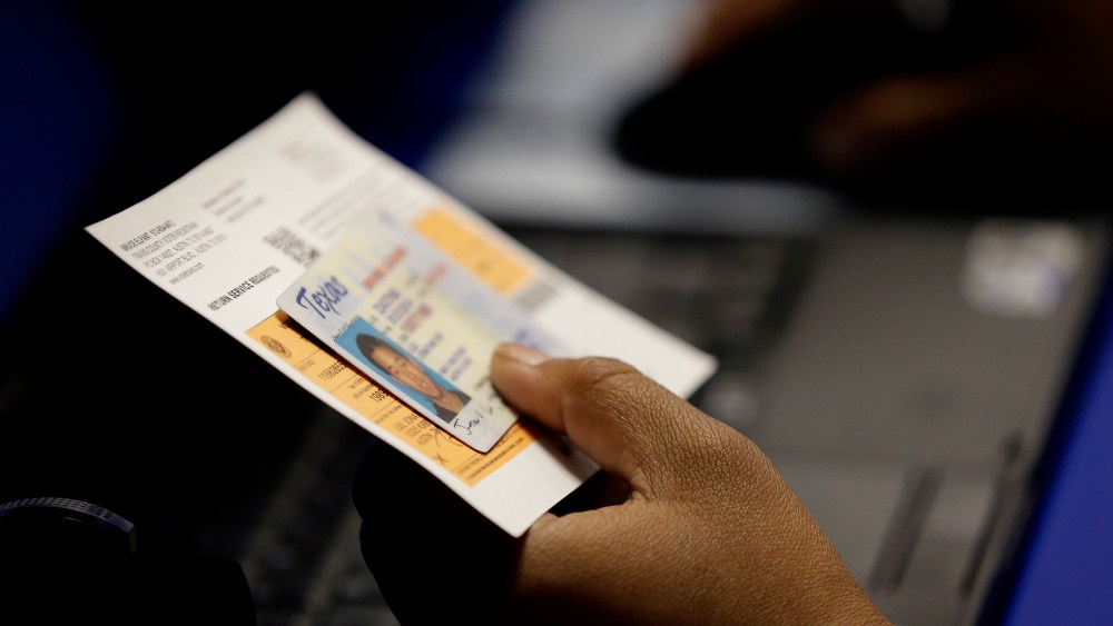 An election official checks a voter's photo identification at an early voting polling site, in Austin, Texas. (Eric Gay/AP)