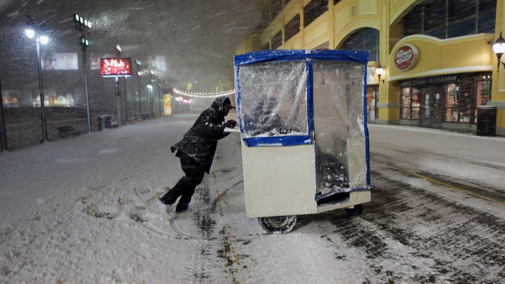 A man maneuvers his Push cart with passengers during a snowstorm early Jan. 23, 2016, on the Atlantic City Boardwalk. (Photo by Mel Evans/AP)