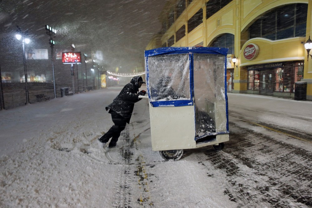 A man maneuvers his Push cart with passengers during a snowstorm early Jan. 23, 2016, on the Atlantic City Boardwalk. (Photo by Mel Evans/AP)