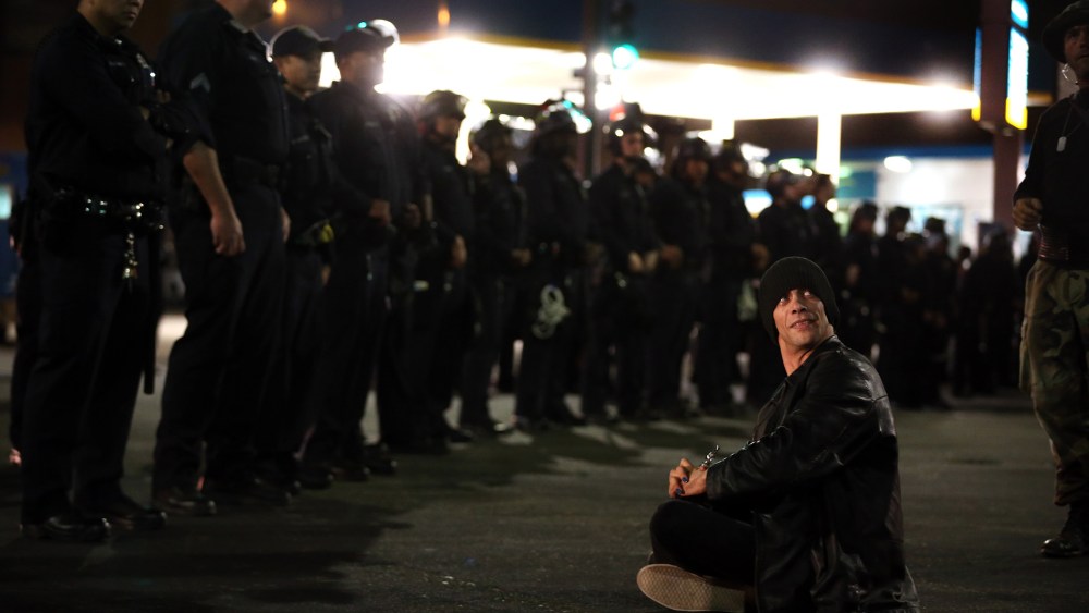 Victor Licata sits in front of Oakland police officers during a protest against Mayor Libby Schaaf's curfew policy in Oakland, Calif., June 5, 2015. (Photo by Ray Chavez/Bay Area News Group/AP)