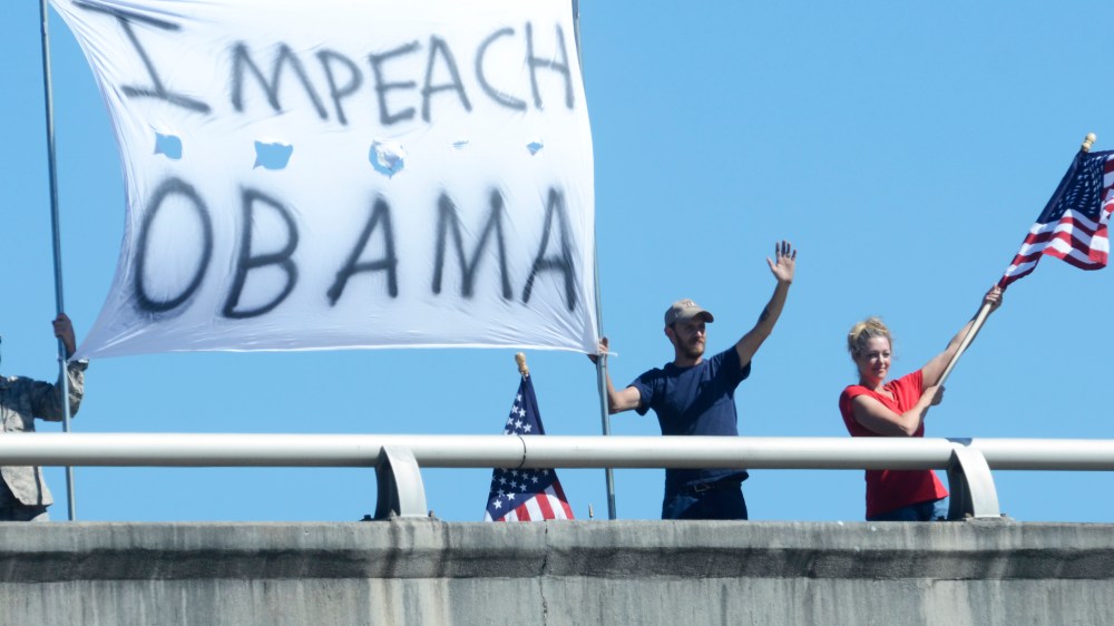 In this photo taken Friday, October 11, 2013, Doug Bearden, Jonathan Branyon and Christine Reno, from left, wave flags and hold an "Impeach Obama" sign