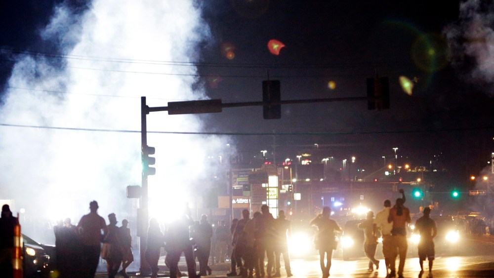 Protesters walk through a cloud of tear gas Monday, Aug. 18, 2014, in Ferguson, Mo.