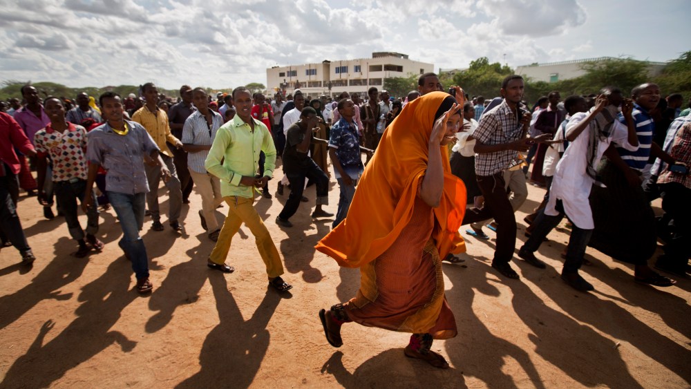 Members of the public run to get a glimpse as authorities display the bodies of the alleged attackers before about 2,000 people in a large open area in central Garissa, Kenya, April 4, 2015. (Photo by Ben Curtis/AP)