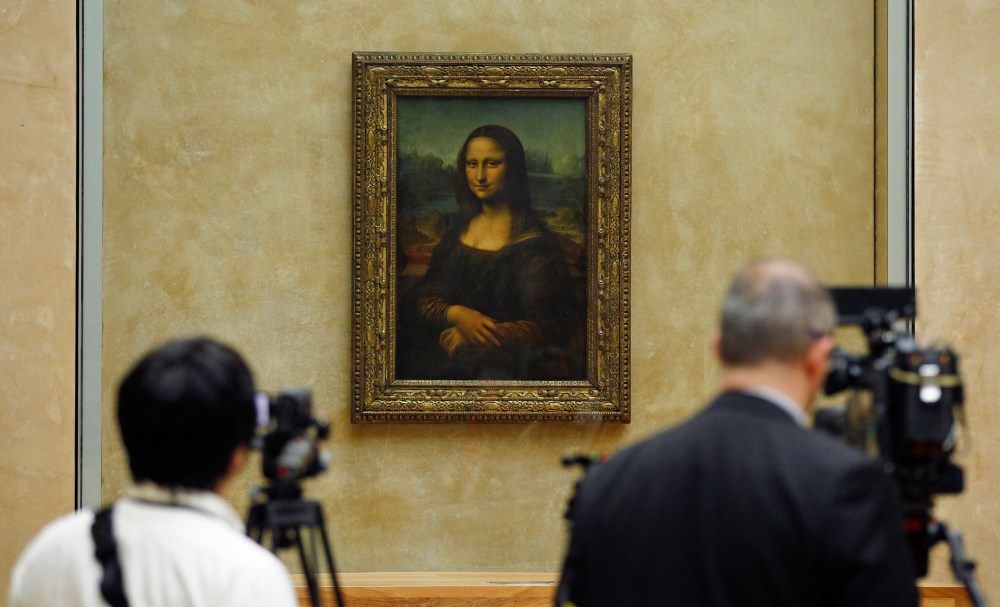 Members of the media are gathered next to the Mona Lisa, during an event to unveil the new lighting of Leonardo da Vinci's painting Mona Lisa, also known as La Joconde, at the Louvre museum in Paris, Tuesday June 4, 2013.